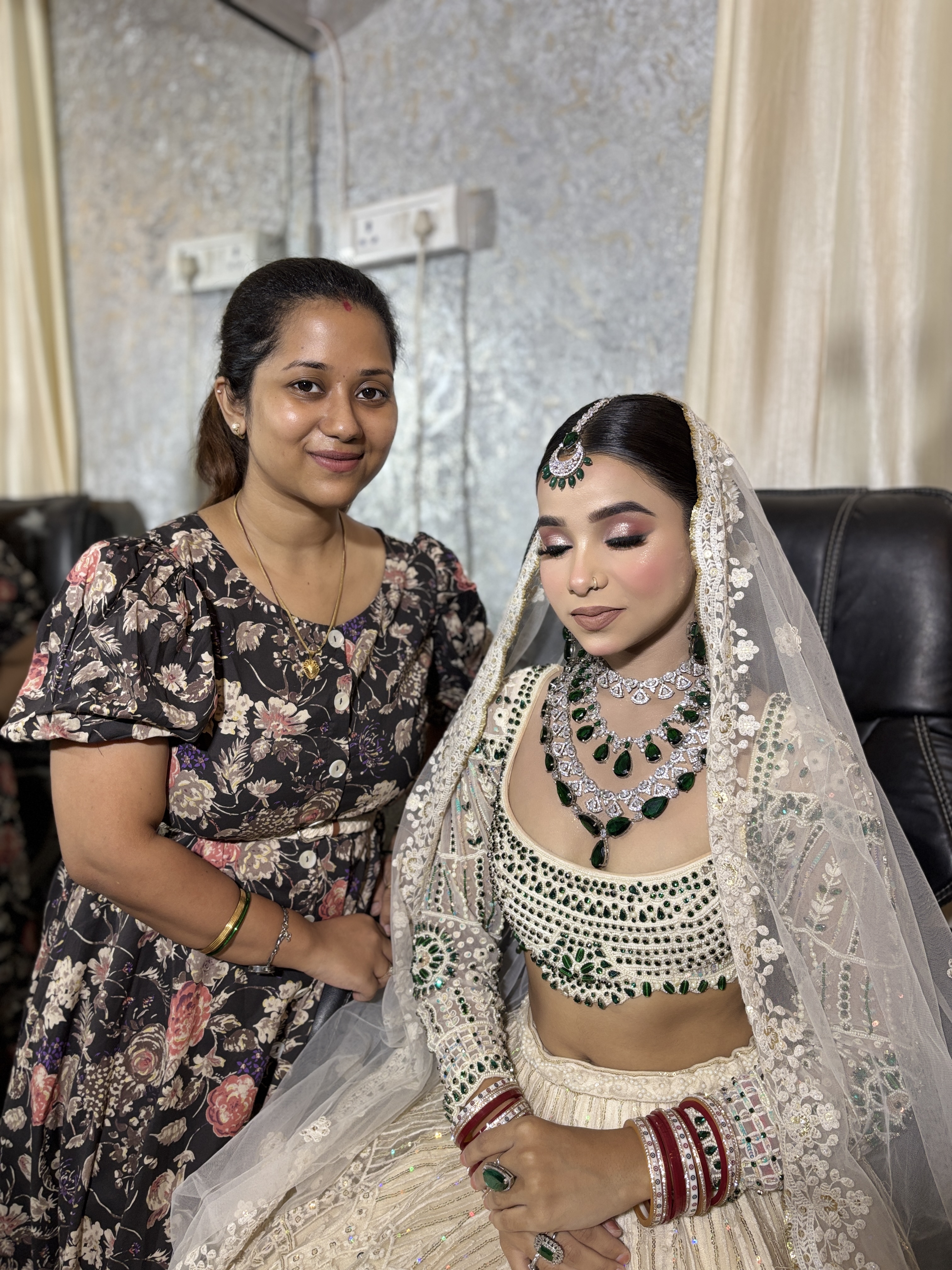 Artist Shreya Chaudhary with bride dressed in an ivory and emerald bridal lehenga with embroidered veil